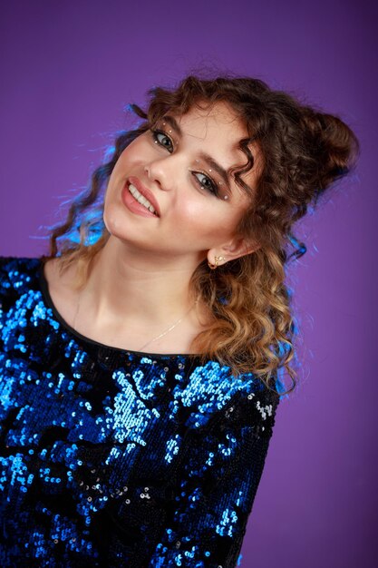 A vertical portrait of a young curlyhaired girl wearing gilded clothes and smiling High quality photo