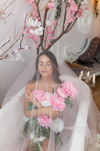 Vertical portrait of young girl sitting under tulle with flowers at bath tube High quality photo