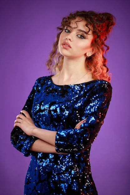 A vertical portrait of a young lady crossed her hands and looked at the camera on purple background High quality photo