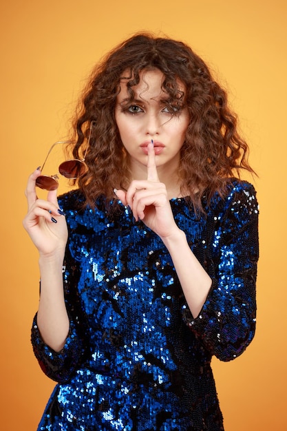 Vertical portrait of young lady holding sunglasses and gesture silent High quality photo