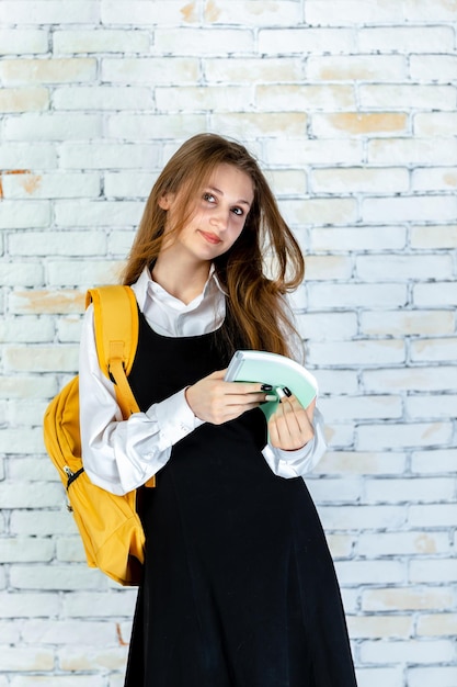 Free photo vertical portrait of young schoolgirl holding notebook and looking at the camera