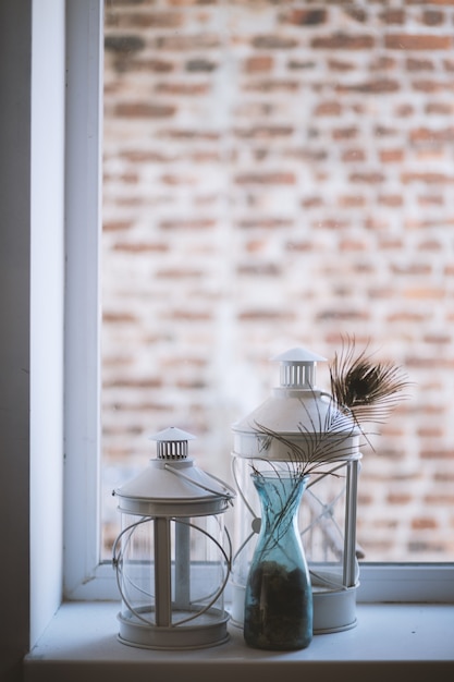 Free Photo vertical selective closeup shot of large and medium glass lantern lamps on a windowsill