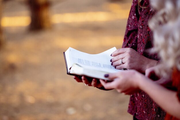 Vertical selective focus shot of two ladies holding a book