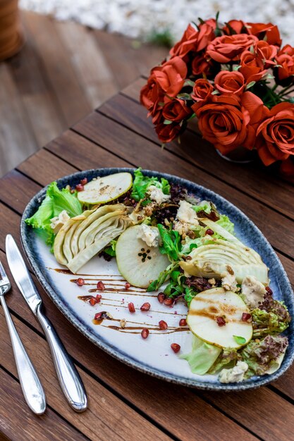 Vertical selective focus shot of vegetable salad on wooden table