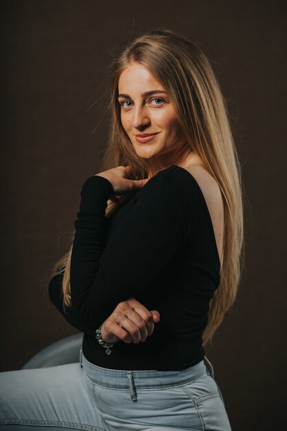 Vertical shot of an attractive blonde female posing while sitting on a barstool