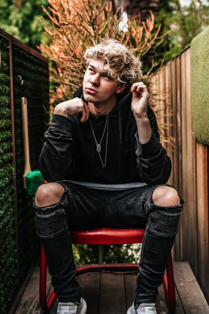 Vertical shot of an attractive male thinking while sitting on a red chair