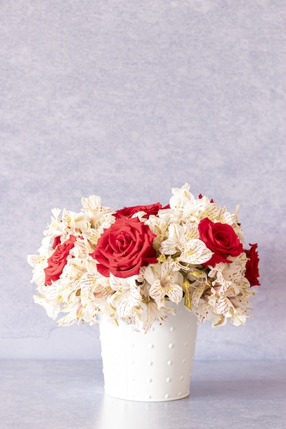 Vertical shot of a beautiful bouquet with red roses and lily flowers in a box