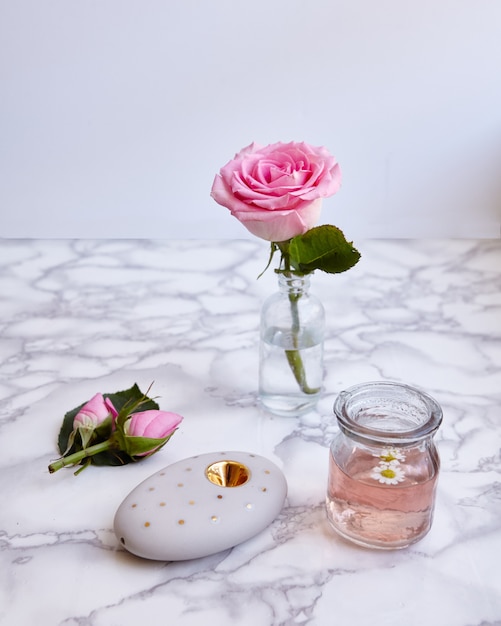 Free Photo vertical shot of a beautiful pink rose and floral objects on a surface