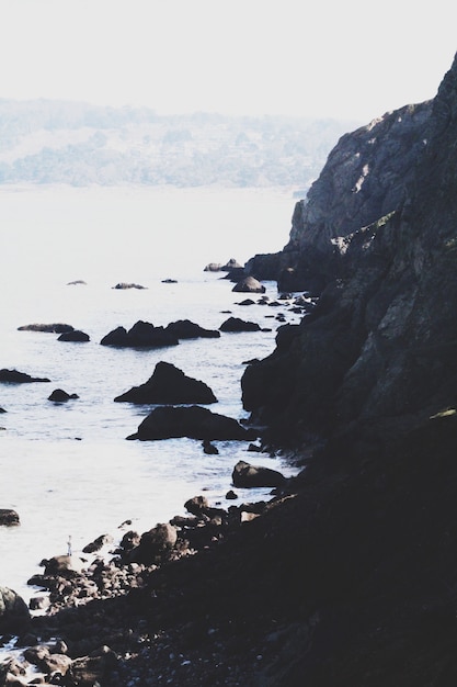 Free photo vertical shot of the beautiful sea with high rocky cliffs on the left