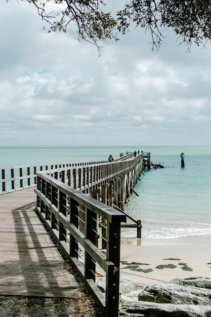 Free Photo vertical shot of the beautiful view of the ocean with a wooden pier on the coast