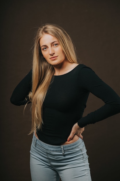 Vertical shot of an blonde female posing while sitting on barstool