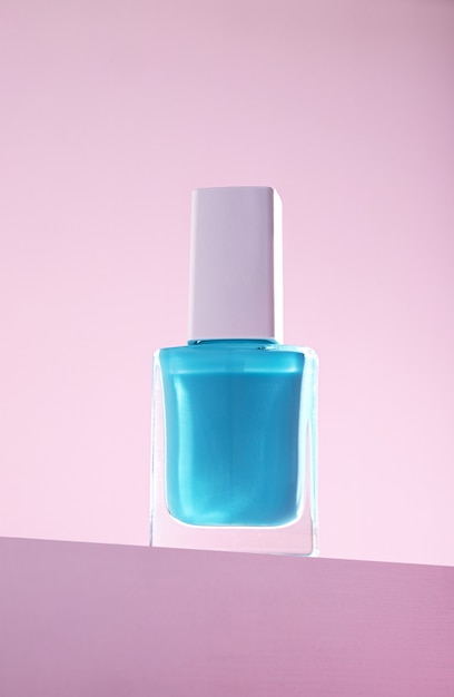 Vertical shot of blue nail polish against a pink wall