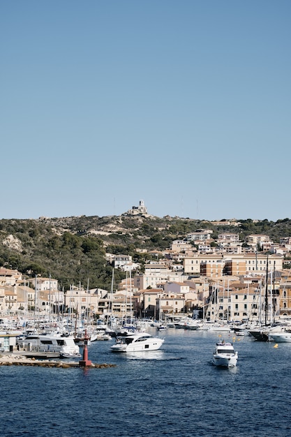 Free photo vertical shot of boats on the water near buildings on the hill with a blue sky in the