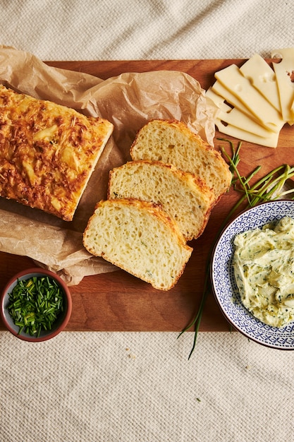 Free photo vertical shot of bread with cheese herbal butter on a wood