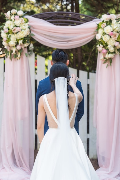 Free photo vertical shot of a bride and a groom posing in a park