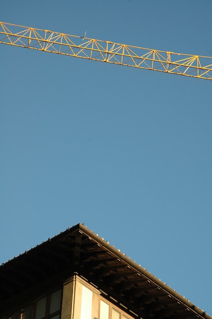 Free photo vertical shot of a building's roof and a crane with a clear sky