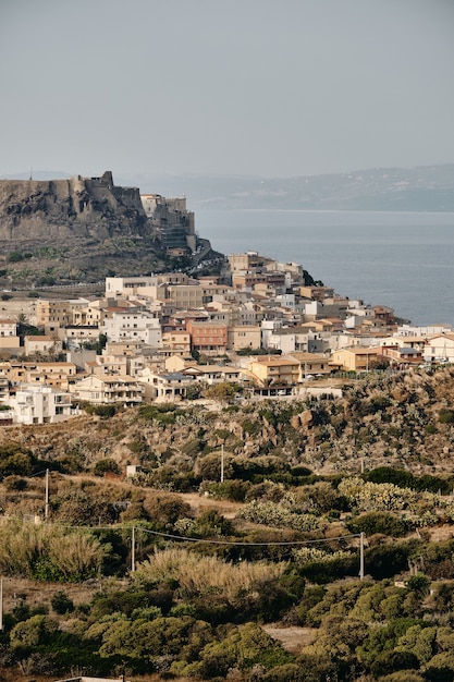 Free photo vertical shot of buildings on the hill near the sea under a blue sky at daytime