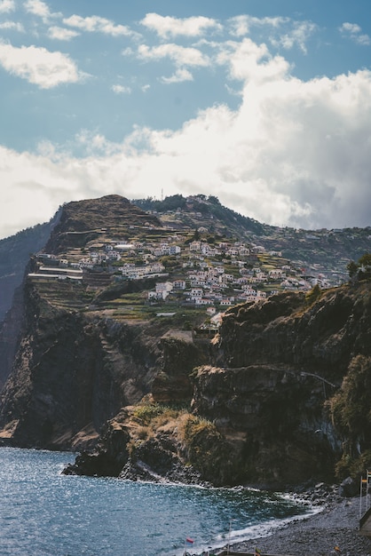 Vertical shot of buildings on the mountain under a blue sky in Funchal, Madeira, Portugal.