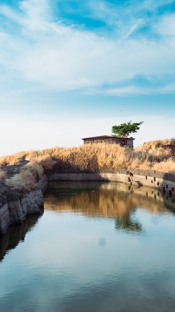 Free photo vertical shot of cabin by the lake under a cloudy sky