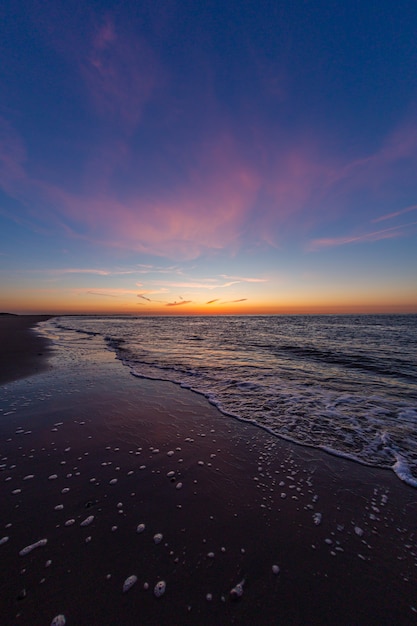 Free Photo vertical shot of the calm ocean during the sunset in vrouwenpolder, zeeland, netherlands