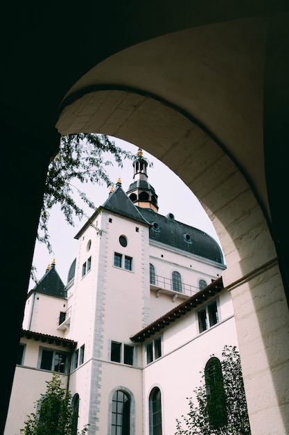 Vertical shot of a cathedral and the trees captured from an arch shaped hallway