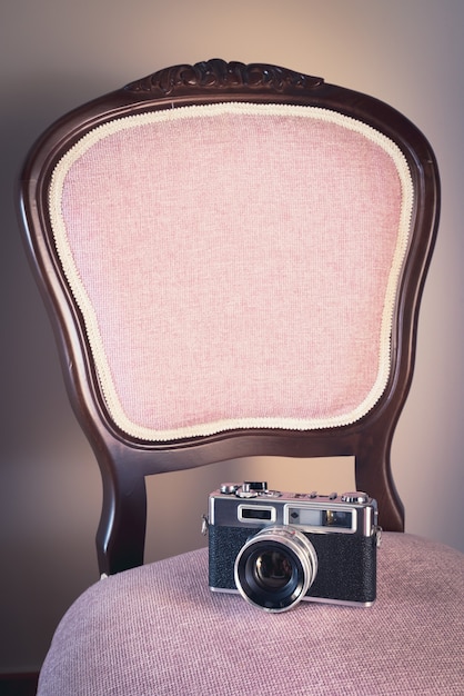 Free photo vertical shot of a chair with a vintage photo camera on it