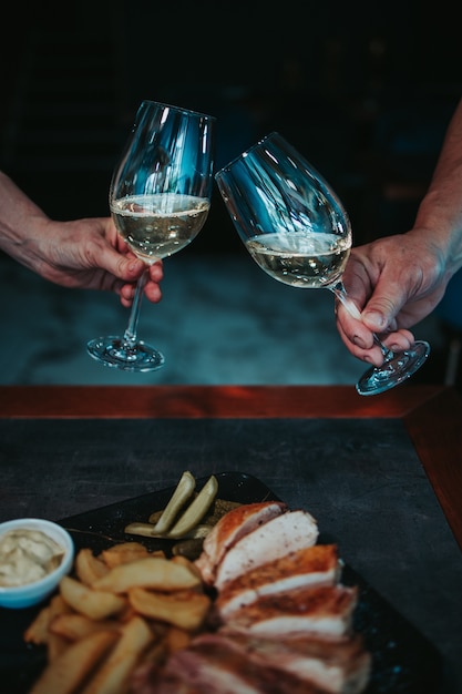 Vertical shot of chicken breast and grilled potatoes in a plate and wine