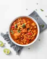 Free photo vertical shot of chickpea curry chana masala with lime in a bowl on a white surf