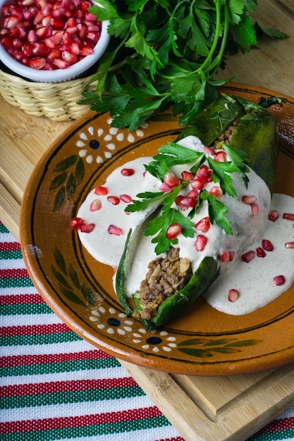 Free photo vertical shot of chiles en nogada in a plate on a wooden board on the table