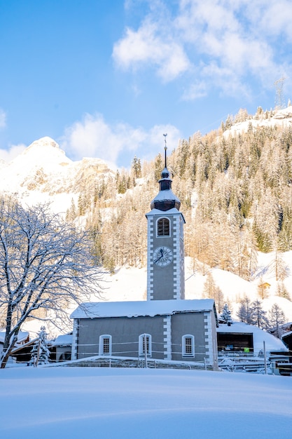 Vertical shot of a clock tower with snow-covered mountains