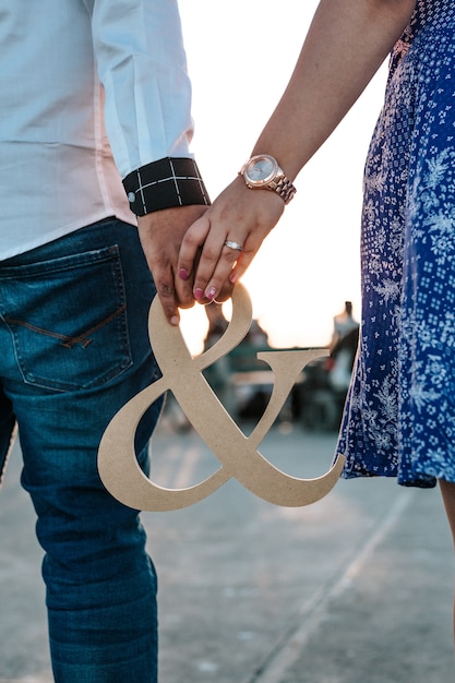 Free photo vertical shot of a couple holding ampersand decoration