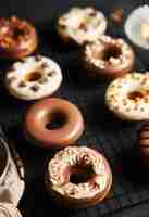 Free photo vertical shot of delicious donuts covered in the white and brown chocolate glaze on a black table