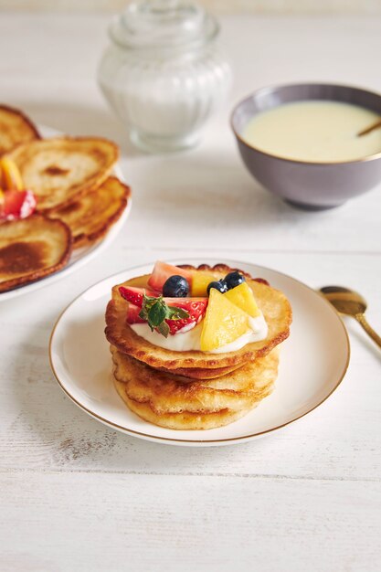 Vertical shot of delicious pancakes with fruits on the top at breakfast