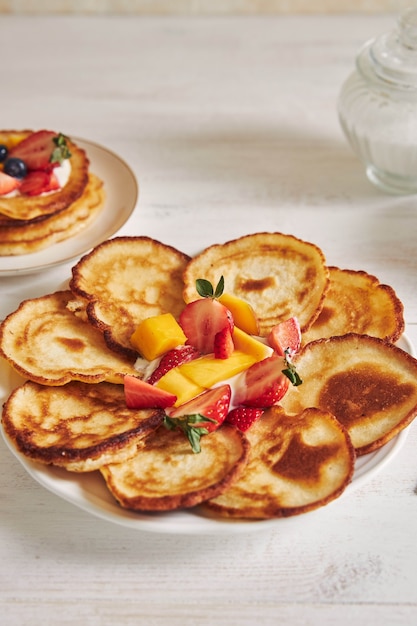 Vertical shot of Delicious Pancakes with fruits on a white wood Table