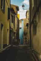 Free photo vertical shot of an empty alley aligned with old yellow buildings leading to a blue building