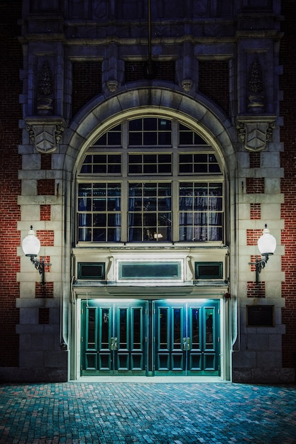 Free Photo vertical shot of the facade of an old brick goth building with lit lamps, at night