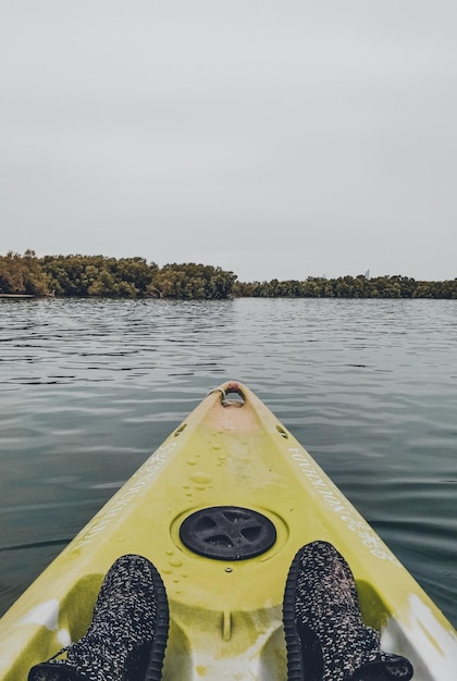 Free Photo vertical shot of feet with sports shoes in the yellow boat on the wavy water