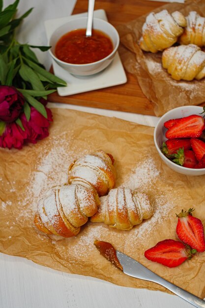 Vertical shot of freshly baked croissants with strawberries and jam