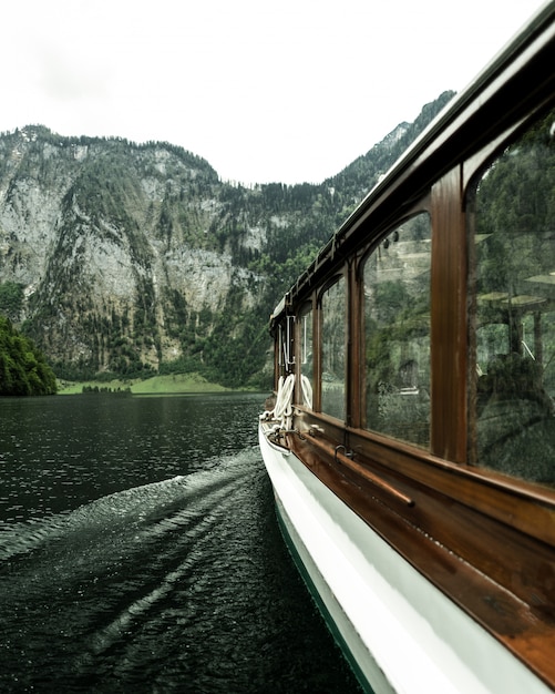 Free Photo vertical shot from the boat sailing on the water with forested mountains in the distance