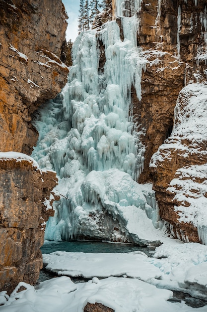 Free photo vertical shot of a frozen waterfall surrounded by rock formations