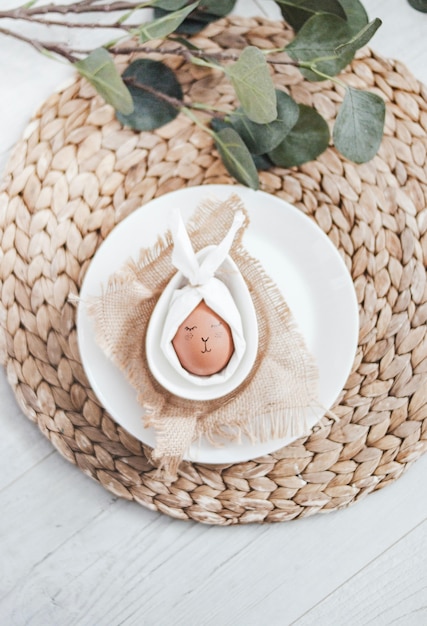 Vertical shot of a funny Easter egg decor in a plate with green leaves