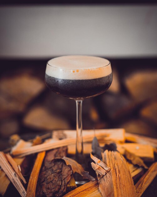 A vertical shot of a glass of delicious espresso martini on the table with a blurry background