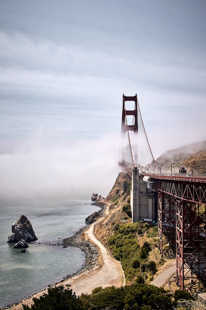 Vertical shot of The Golden Gate Bridge against a misty blue sky in San Francisco, California, USA