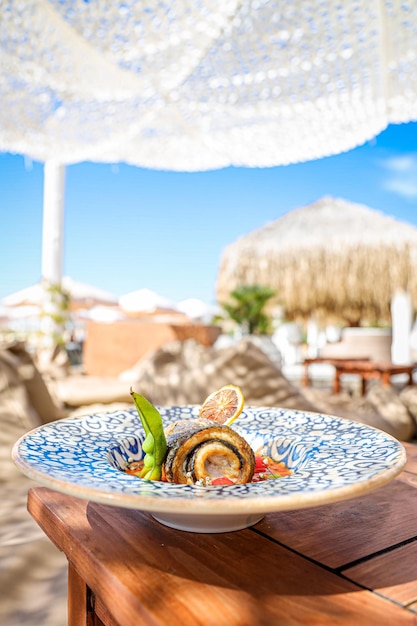 Free photo vertical shot of a gourmet fish dish at a beachside restaurant