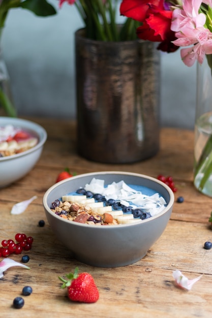 Vertical shot of a healthy blueberry smoothie bowl with fruits and granola