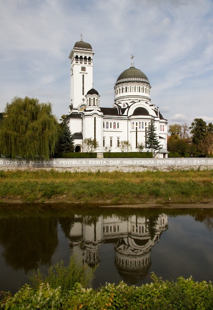 Free photo vertical shot of the holy trinity cathedral reflecting in the lake in sighisoara  romania