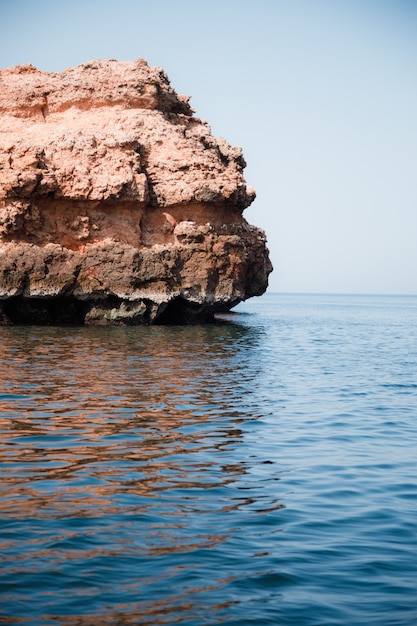 Free photo vertical shot of a huge stone in the middle of the calm sea