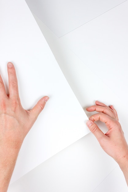 Free photo vertical shot of human hands holding a piece of white paper