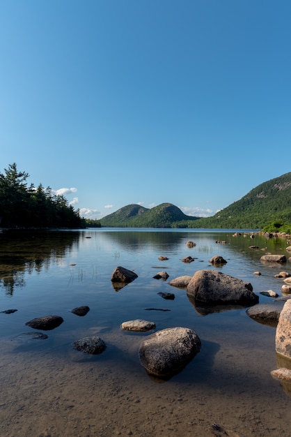 Free photo vertical shot of a lake with big stones and the reflection of the sky in it