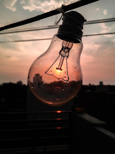 Free photo vertical shot of a light bulb against the sunset sky